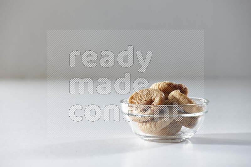 A glass bowl full of dried figs on a white background in different angles