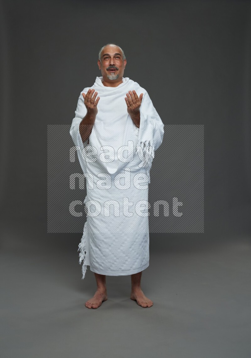 A man wearing Ehram Standing dua'a on gray background