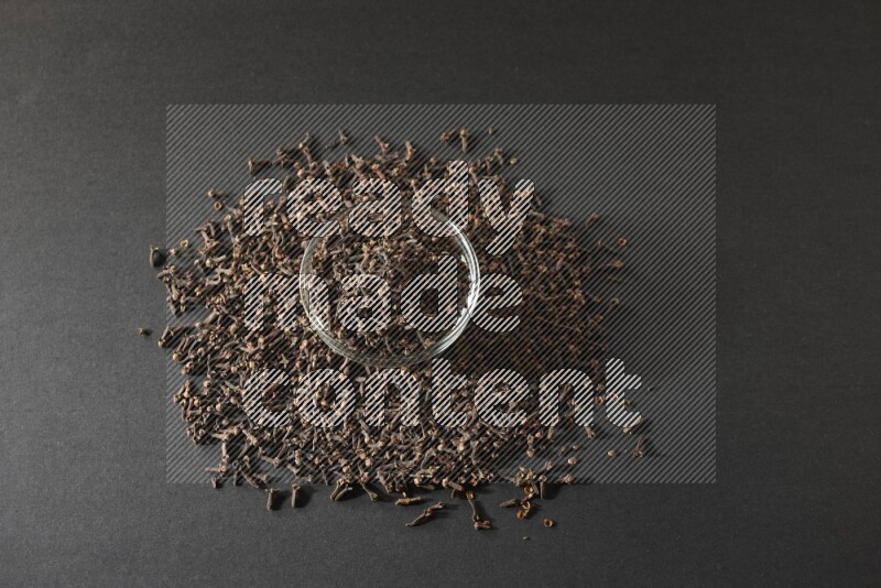 A glass bowl full of cloves on a black flooring