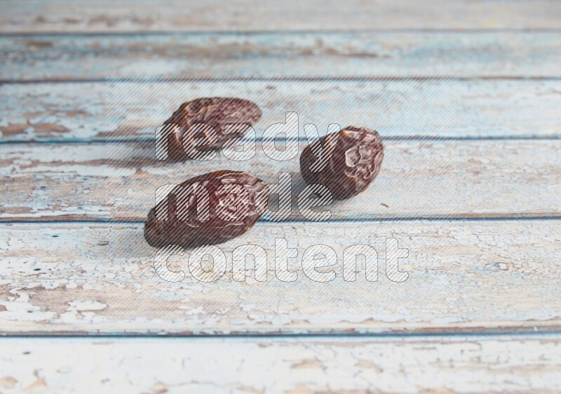 three madjoul dates on a light blue wooden background