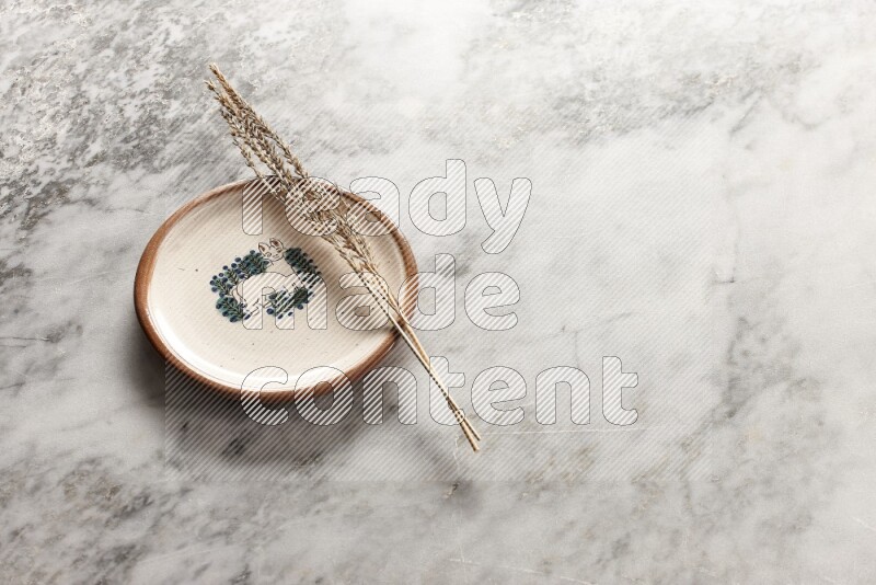 Wheat stalks on decorative pottery plate on grey marble background