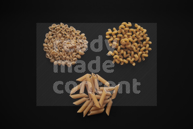 Different pasta types in bunches on black background