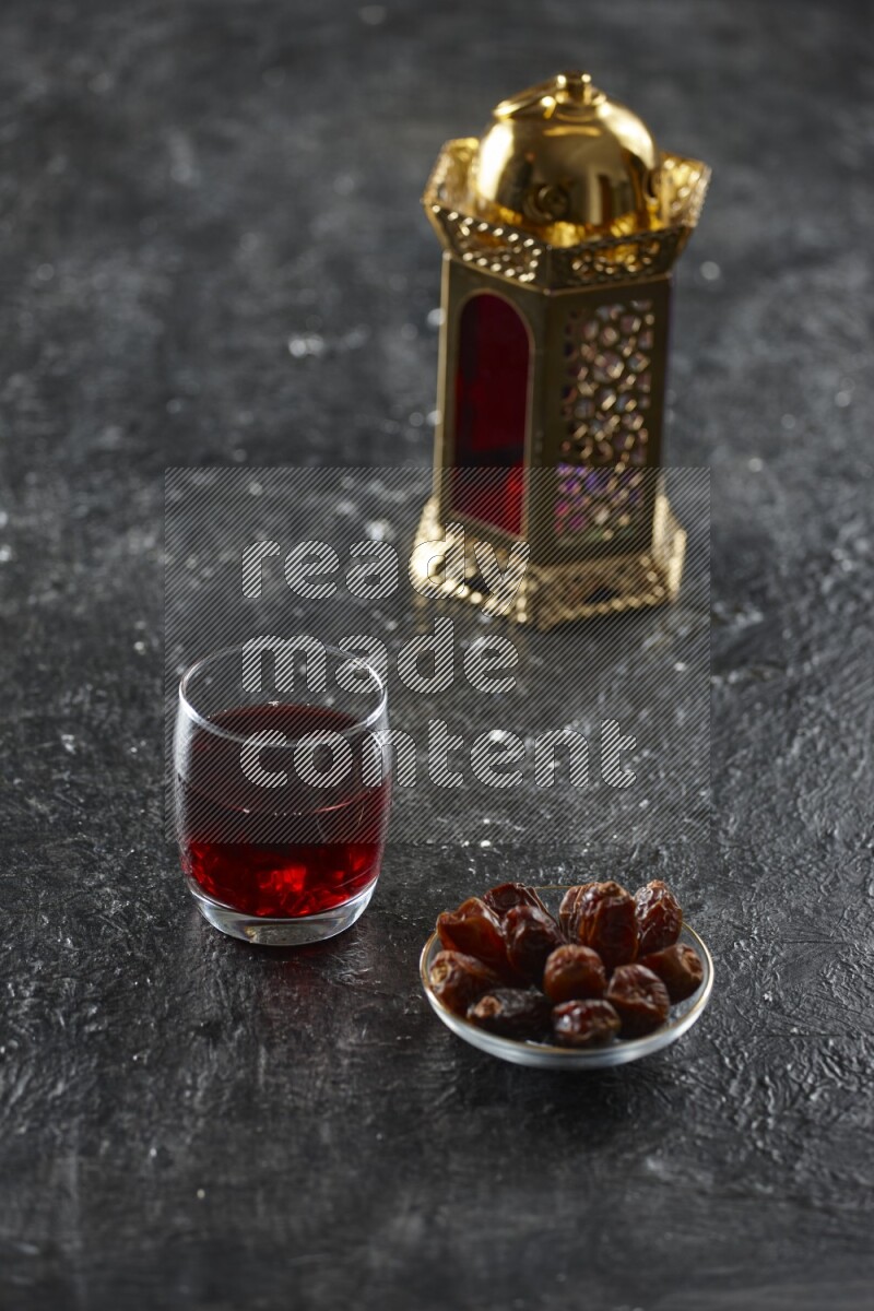 A golden lantern with different drinks, dates, nuts, prayer beads and quran on textured black background
