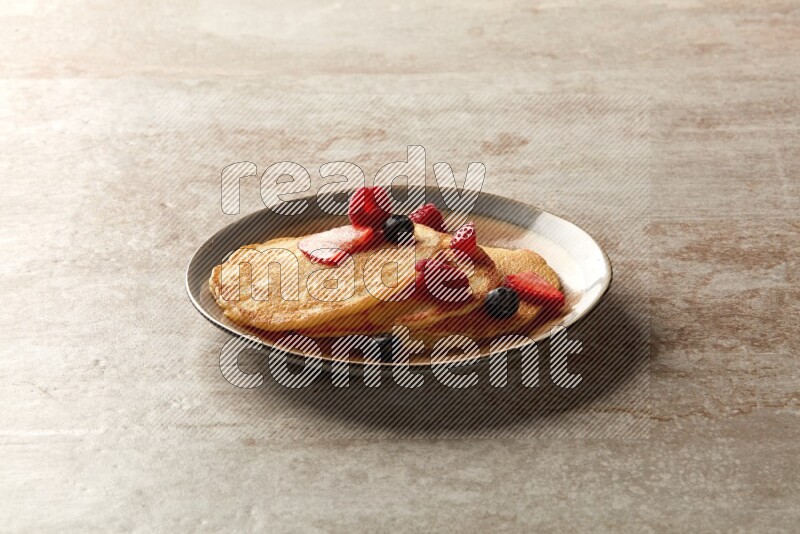 Three stacked mixed berries pancakes in a bicolor plate on beige background