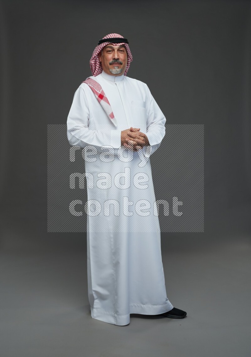 Saudi man with shomag Standing Interacting with the camera on gray background