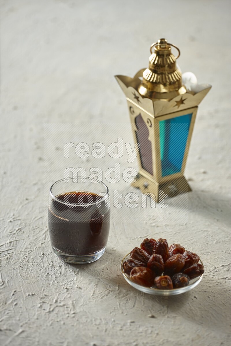 A golden lantern with different drinks, dates, nuts, prayer beads and quran on textured white background