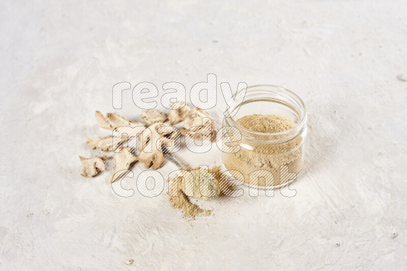A glass jar full of ground ginger powder on white background