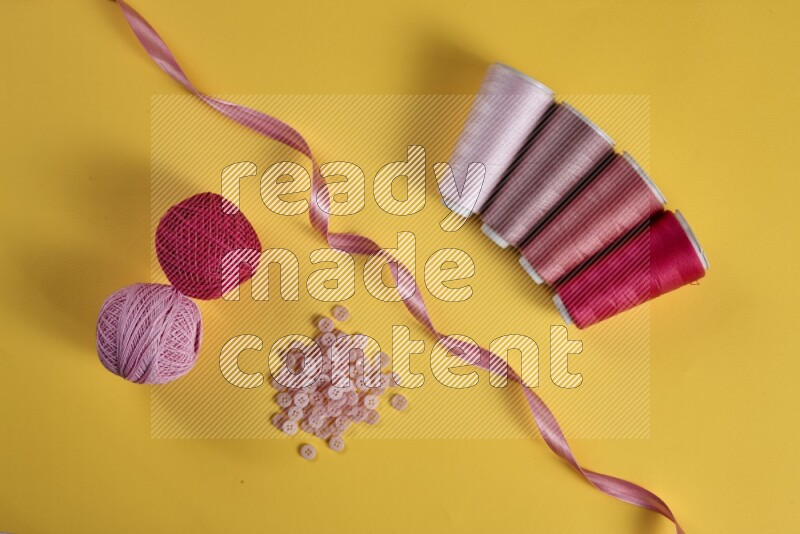 A pink collection of sewing and tailoring tools arranged on a yellow background