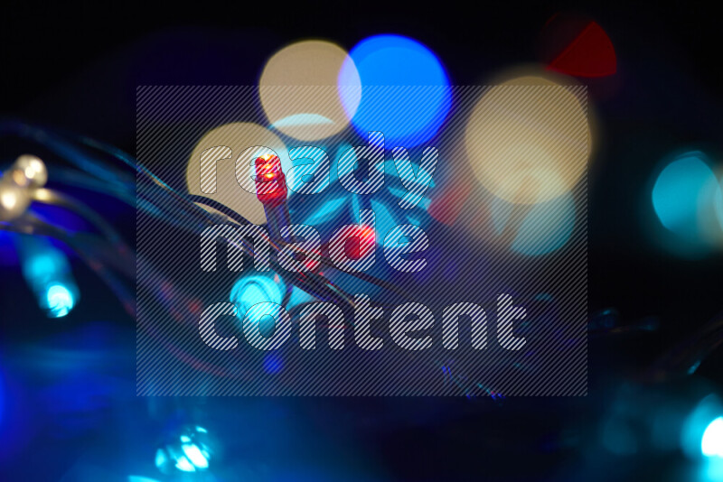 Light bulbs glowing against backdrop of multicolord bokeh