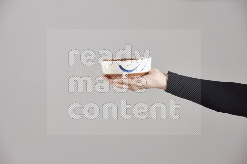 A woman in black abaya holding different pottery essentials in different positions