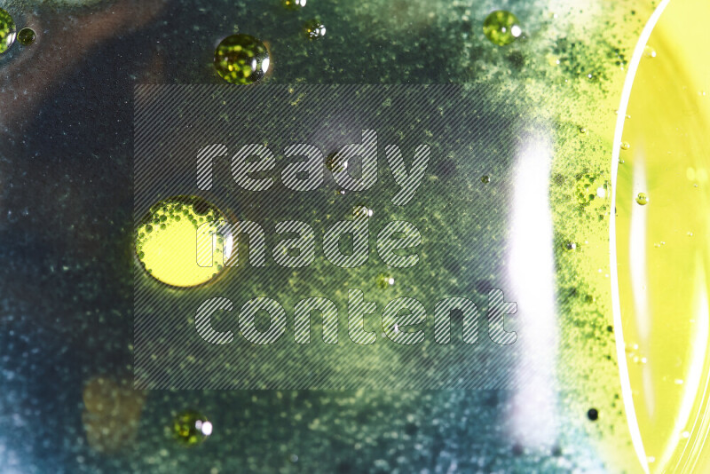 Close-ups of abstract green and yellow watercolor drops on oil Surface on white background
