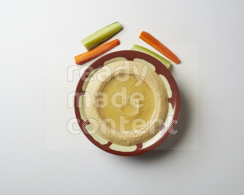 Hummus in a traditional plate garnished with olive oil on a white background