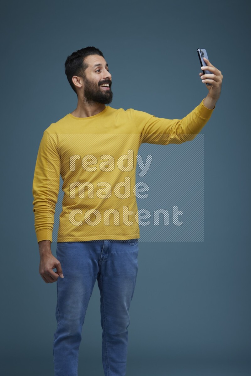 Man Taking a Selfie  in a blue background wearing a yellow shirt