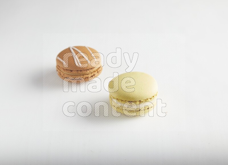 45º Shot of of two assorted Brown Irish Cream, and Yellow Lime macarons on white background