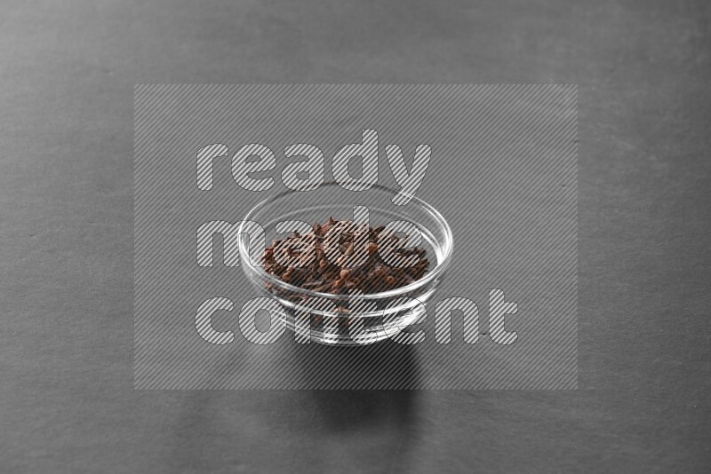 A glass bowl full of cloves on black flooring