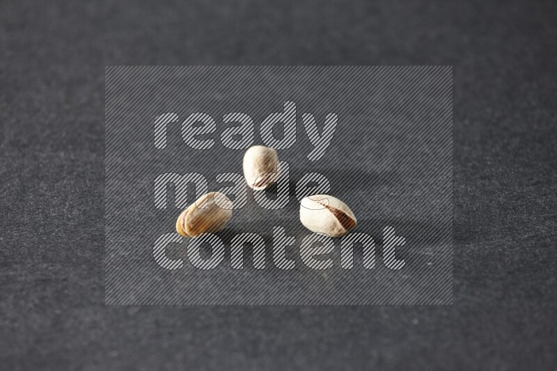 3 pistachios on a black background in different angles