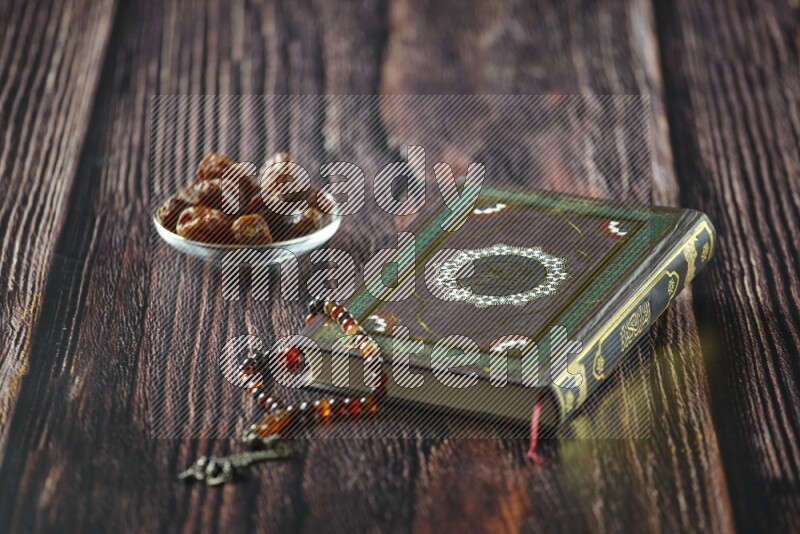 Quran with dates, prayer beads and different drinks all placed on wooden background