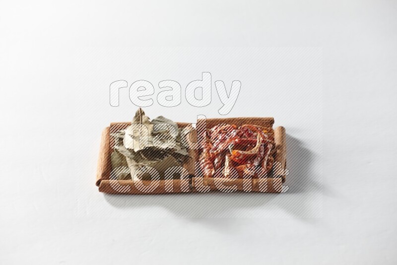 مربعان من أعواد القرفة ممتلئان بالفلفل الحار المجفف وأوراق الغار علي خلفية بيضاء