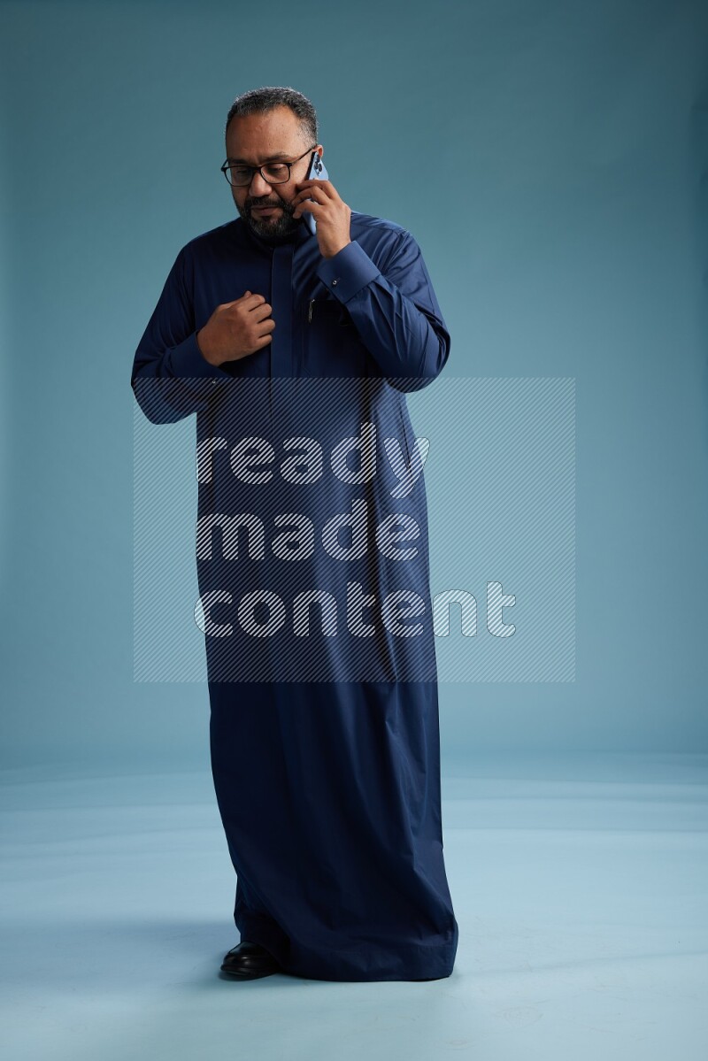 Saudi Man without shimag Standing talking on phone on blue background