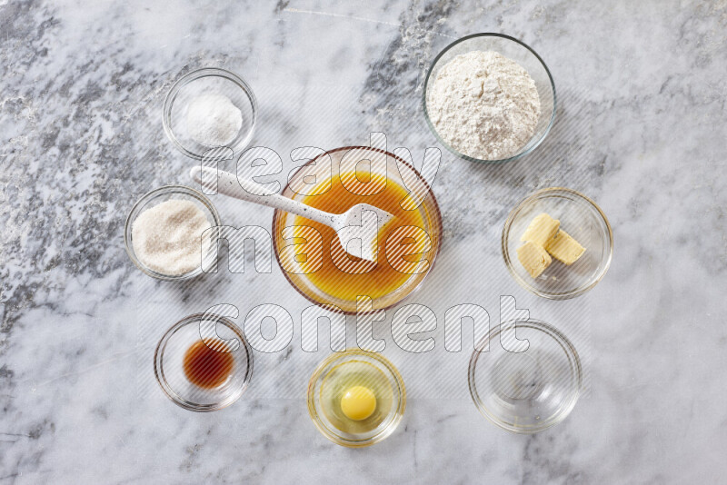 كوكيز خطوة بخطوة بمكوناتها، الدقيق، الزبدة، السكر البني، البيض، الفانيليا، السكر الأبيض، رقائق الشوكولاتة وصودا الخبز على خلفية رخام رمادي