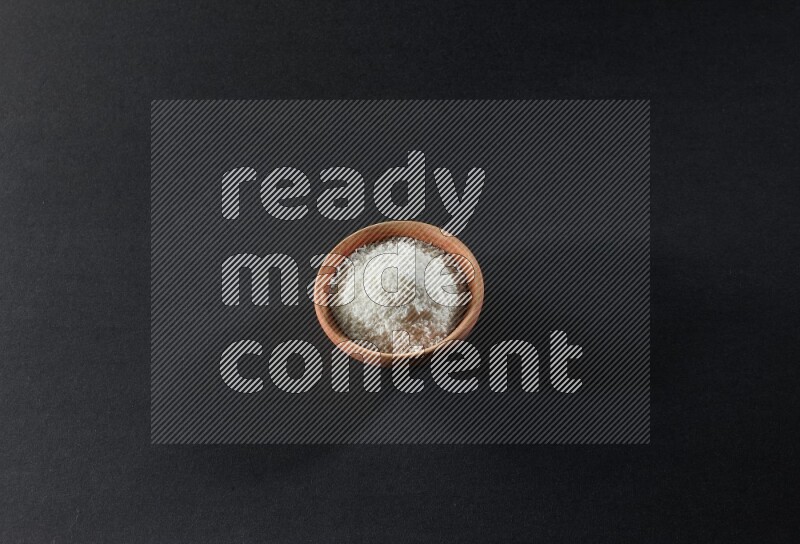 A wooden bowl full of desiccated coconut on a black background in different angles