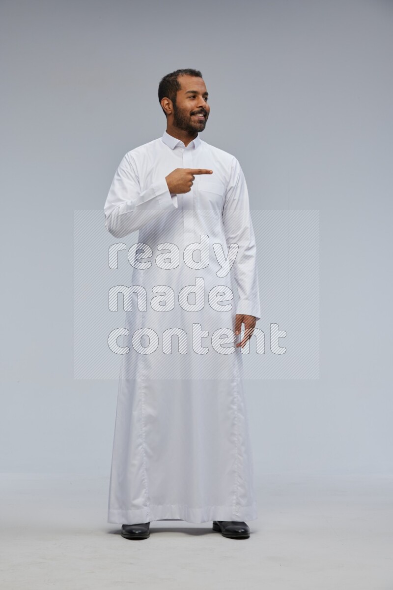 Saudi man Wearing Thob standing interacting with the camera on Gray background