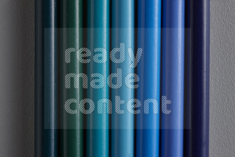 مجموعة من أقلام الرصاص الملونة مرتبة لتعرض تدرجا من الألوان الزرقاء علي خلفية رمادية