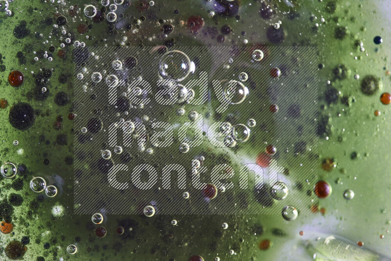 Close-ups of abstract red, green and blue watercolor drops on oil Surface on green background