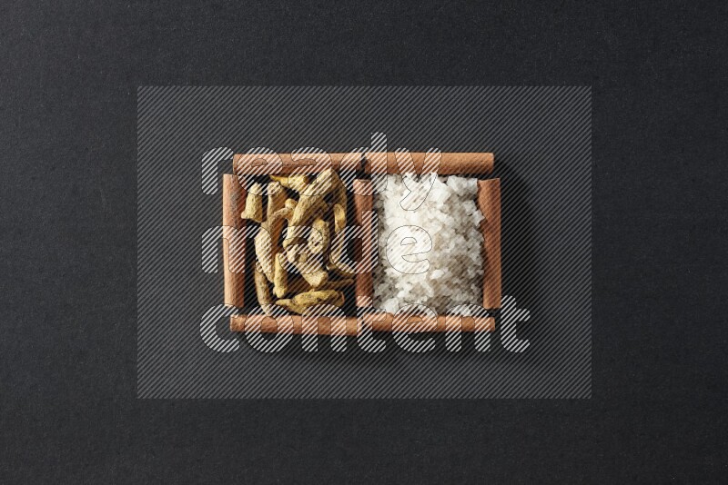 2 squares of cinnamon sticks full of white salt and turmeric fingers on black flooring
