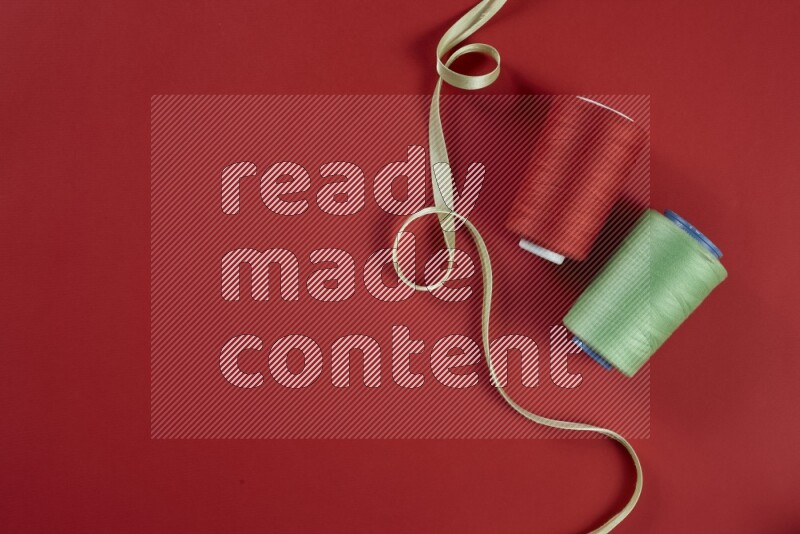 A green and red collection of sewing and tailoring tools arranged on a red background