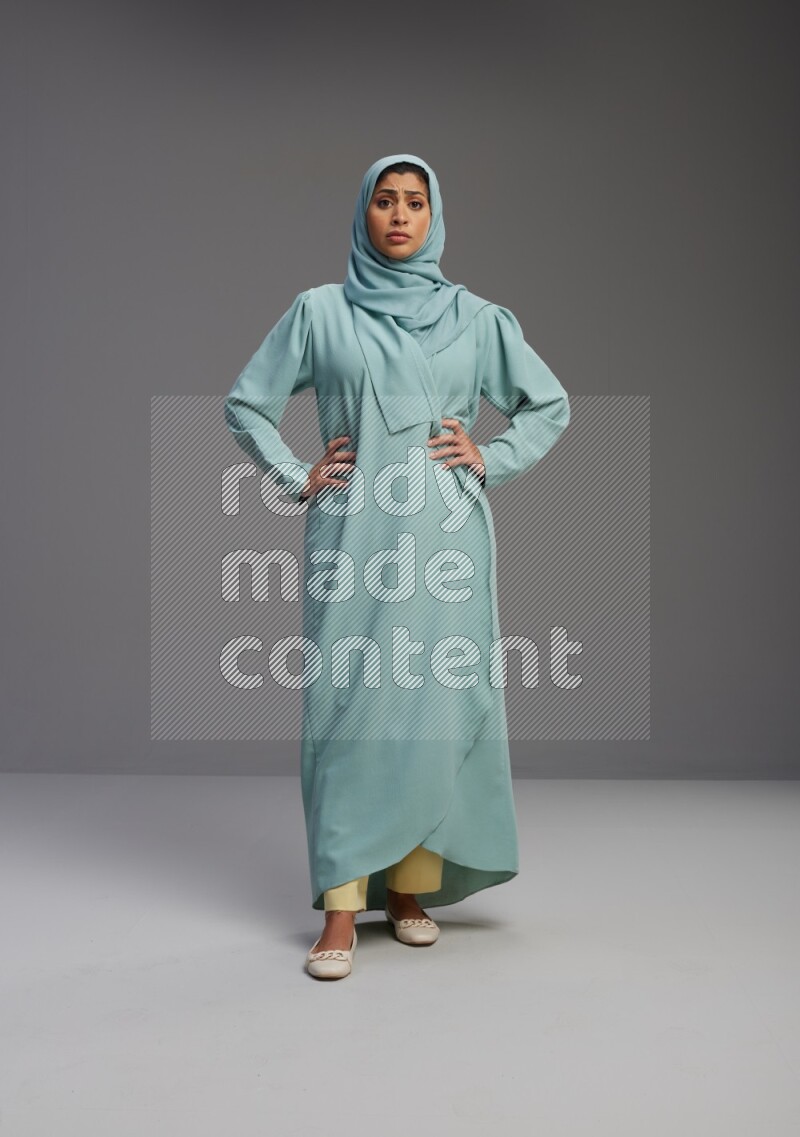 Saudi Woman wearing Abaya standing interacting with the camera on Gray background