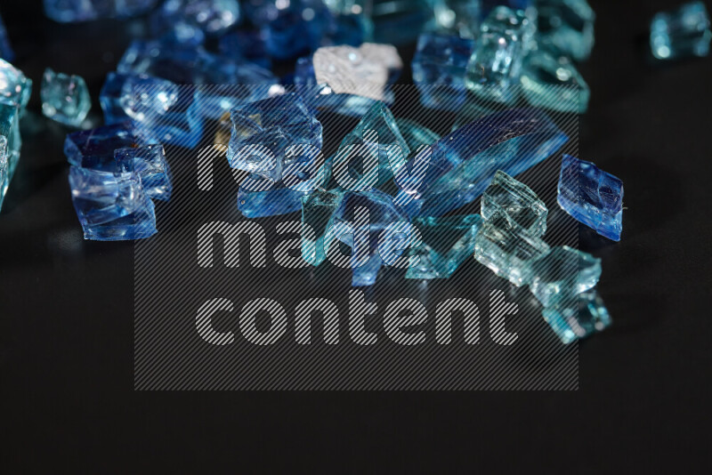 Transparent blue fragments of glass scattered on a black background