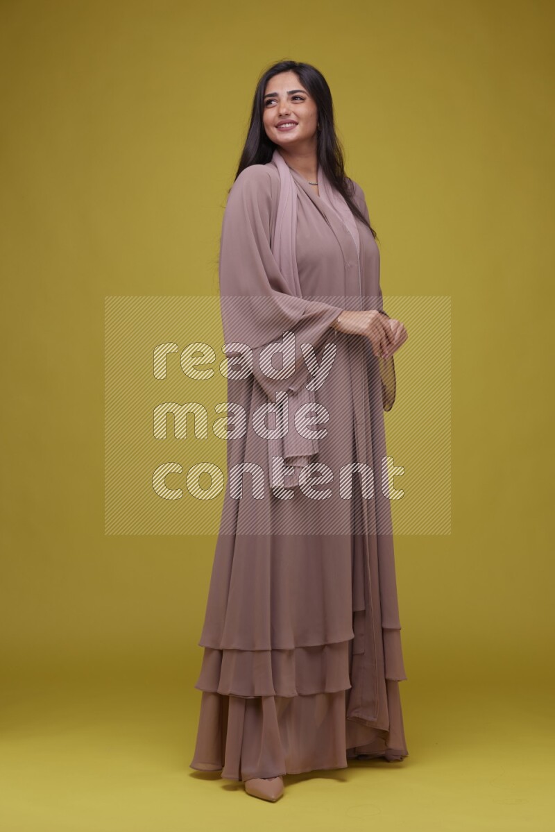 A woman Posing on a Yellow Background wearing Brown Abaya