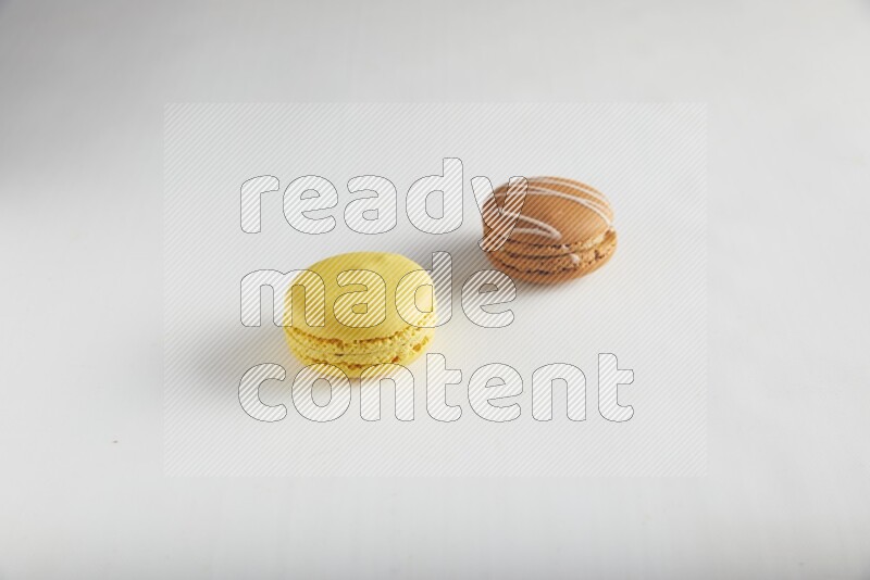 45º Shot of of two assorted Brown Irish Cream, and Yellow Lemon macarons on white background