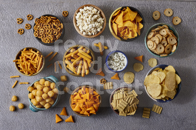 Assorted snacks in pottery bowls on grey background