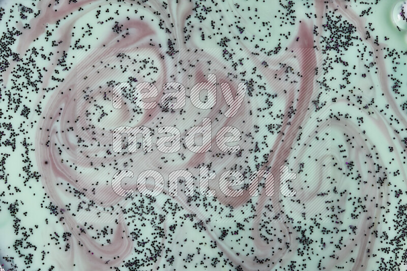 A close-up of swirls of red with sparkling purple glitter scattered on green background