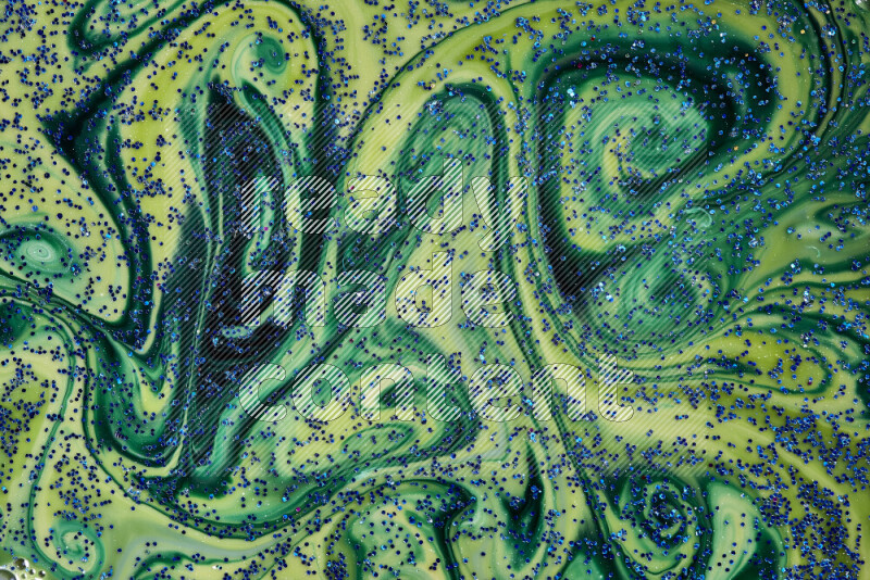 A close-up of sparkling blue glitter scattered on swirling blue and green background