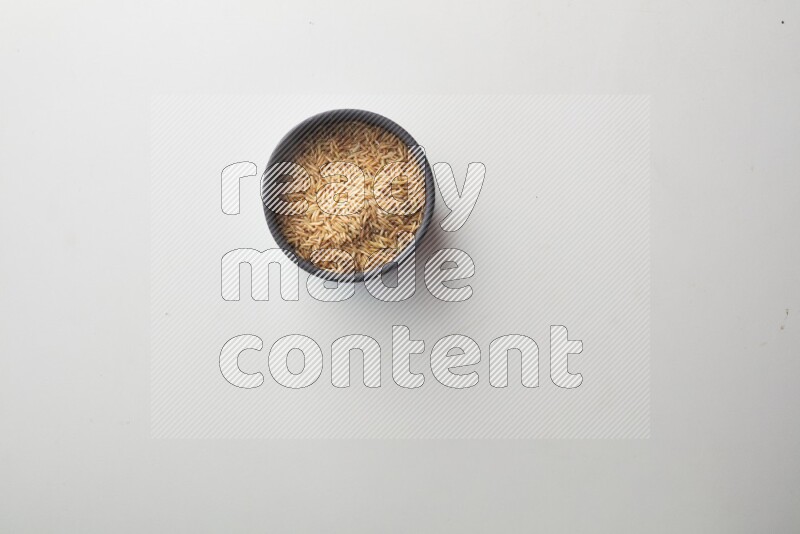 Top-view shot of long grain brown rice in a container on white background