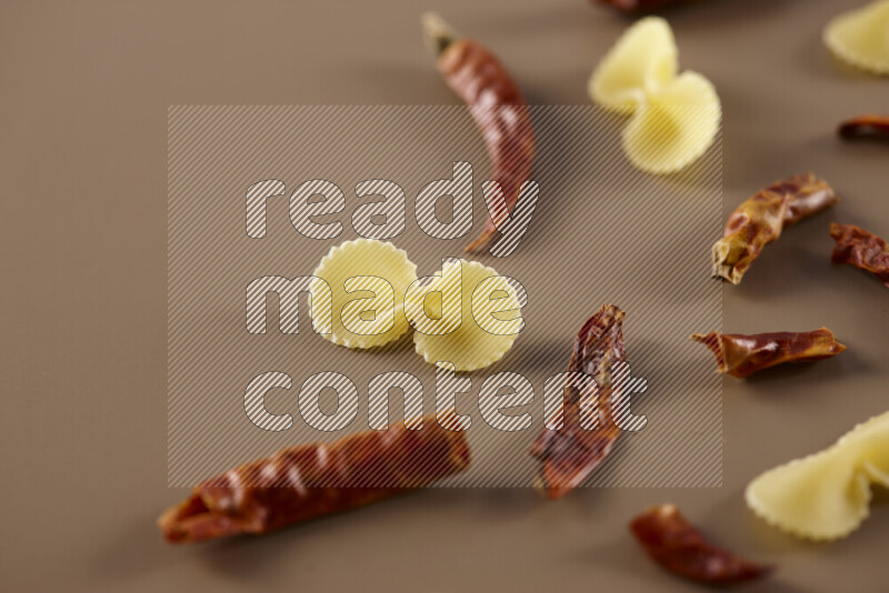 معكرونة مع مكونات متنوعة من الطماطم والثوم والبصل والفلفل الأحمر والفلفل الأسود والفلفل الأبيض وأوراق الغار وإكليل الجبل والهيل على خلفية بيج