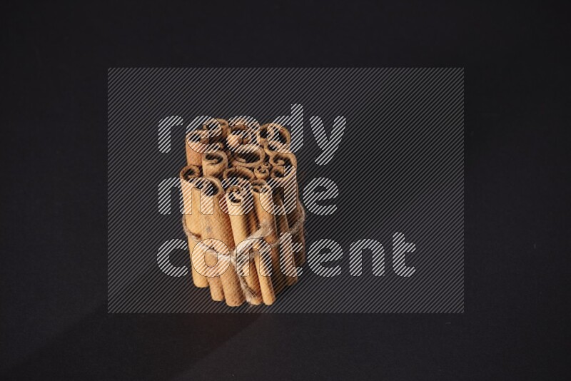 A bounded stack of cinnamon sticks on black background