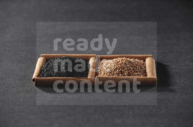 مربعان من أعواد القرفة ممتلئان بحبوب الخردل وحبة البركة السوداء علي خلفية سوداء