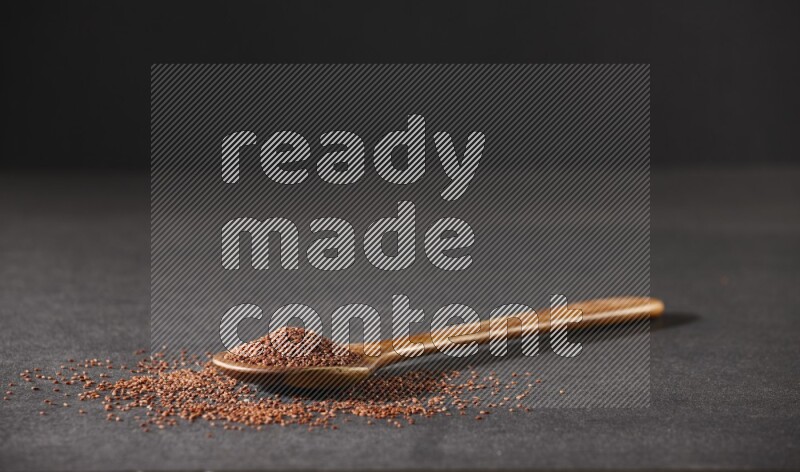 ملعقة خشبية كبيرة ممتلئة ببذور حب الرشاد وبعض البذور متناثرة علي خلفية سوداء