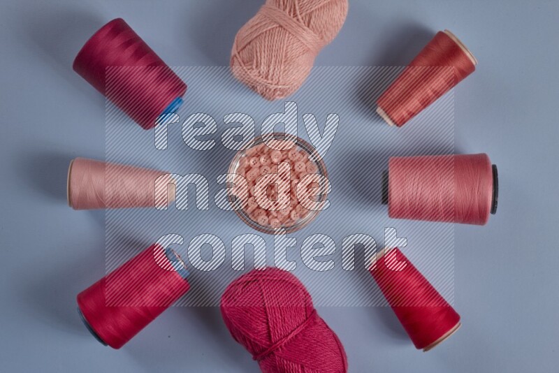 A pink collection of sewing and tailoring tools arranged on a blue background