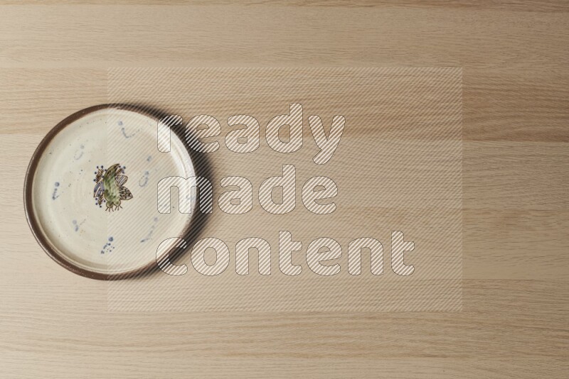 A decorative pottery plate on light wooden background