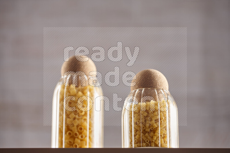 Raw pasta in glass jars on beige background