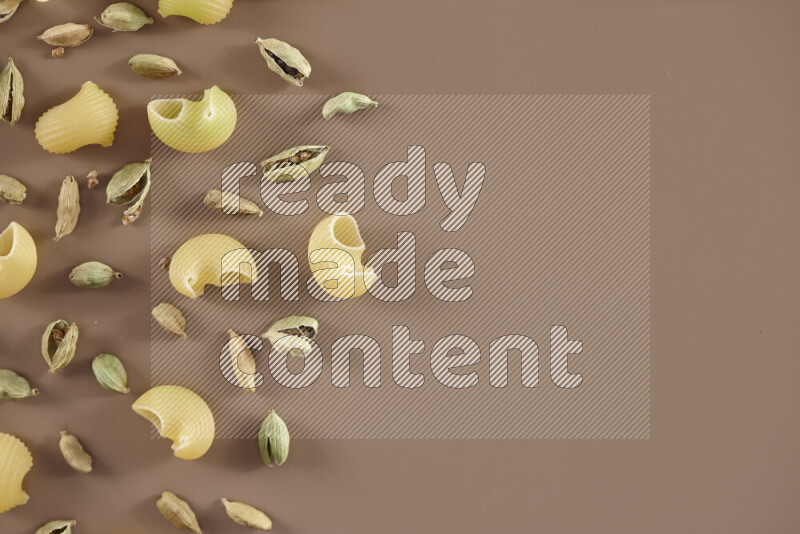 معكرونة مع مكونات متنوعة من الطماطم والثوم والبصل والفلفل الأحمر والفلفل الأسود والفلفل الأبيض وأوراق الغار وإكليل الجبل والهيل على خلفية بيج