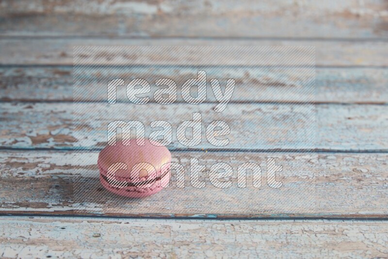 45º Shot of Purple Strawberry macaron on light blue wooden background