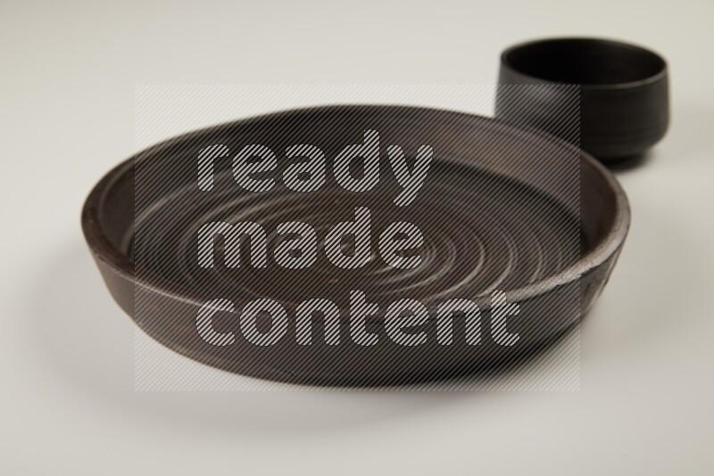 black pottery plate and black bowls on white background