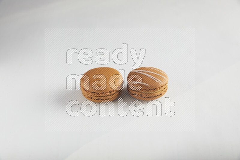 45º Shot of of two assorted Brown Irish Cream, and Brown Maple Taffy macarons  on white background