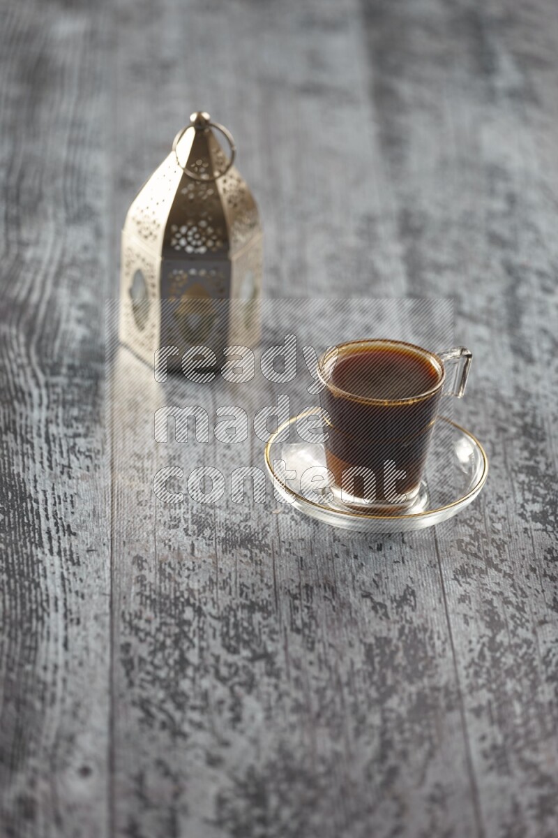 A silver lantern with different drinks, dates, nuts, prayer beads and quran on grey wooden background